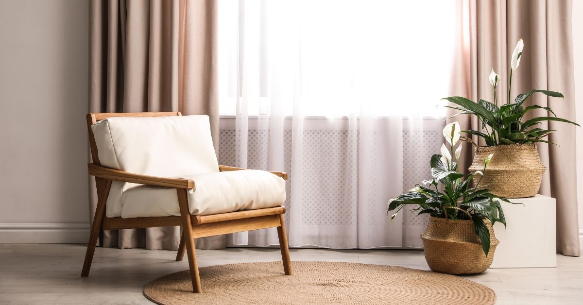 A wooden chair next to window and there are two plant pots on the right side of window