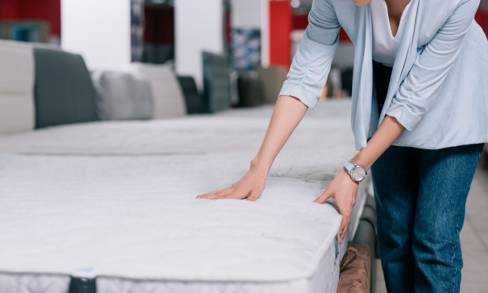 A lady is touching mattress with her two hands