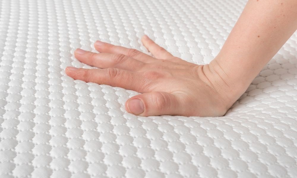Image with a hand pressing the mattress